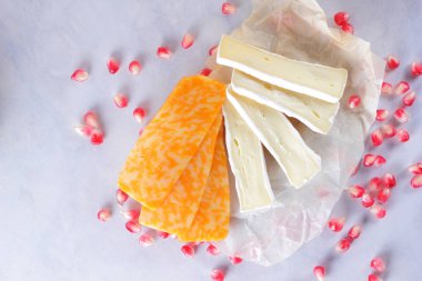 Camembert peyniri, dilimlenmiş peynir, turuncu peynir, peynir bir sürü. Yeşil üzüm ve beyaz zemin üzerine nar taneleri