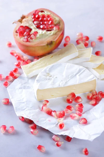 Camembert peyniri, peynir, peynir beyaz zemin üzerine nar taneleri ile bir sürü dilimlenmiş