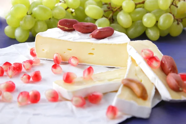 Camembert peyniri, peynir, peynir kalıp, Yeşil üzüm, fıstık ve nar taneleri ile Etiketler için koyu mavi zemin üzerine dilimlenmiş