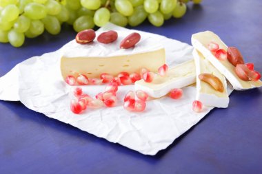 Camembert peyniri, peynir, peynir kalıp, Yeşil üzüm, fıstık ve nar taneleri ile koyu mavi bir arka plan dilimlenmiş