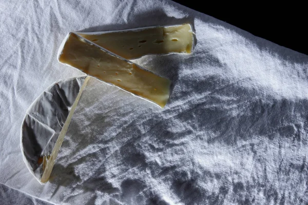 Queijo de camembert cortado em um guardanapo de linho branco em um estilo retro do desenhista — Fotografia de Stock