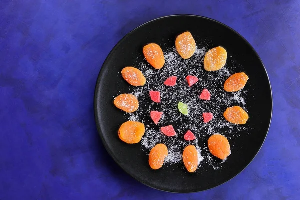 Kuru Kayısı, şekerlenmiş meyve şeker retro tarzı bir koyu mavi arka plan üzerinde siyah bir plaka üzerinde