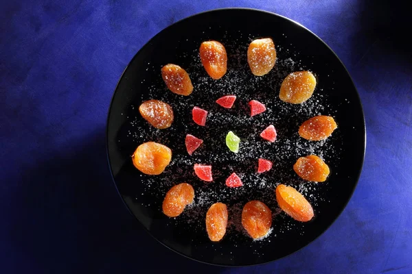 Kuru Kayısı, şekerlenmiş meyve şeker koyu mavi zemin üzerine siyah bir plaka üzerinde