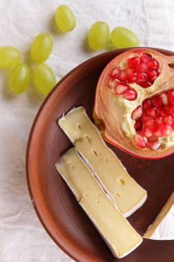 Camembert peyniri, bir bardak kefir, nar, çilek, Yeşil üzüm, fıstık tahıl ve retro tarzı içinde beyaz ve koyu mavi zemin üzerine ekmek