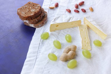 Camembert peyniri, bir bardak kefir, nar, çilek, Yeşil üzüm, fıstık tahıl ve retro tarzı içinde beyaz ve koyu mavi zemin üzerine ekmek