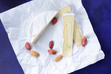 Camembert peyniri, bir bardak süt, nar, fıstık tahıl ve beyaz kumaş üzerine ekmek ve retro tarzı bir koyu mavi arka plan