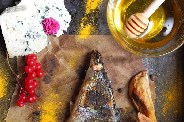 Grilled fish with cheese, honey, rowan, kalina, lemon slices, baked potatoes, pink flowers and spices on parchment paper — Stock Photo, Image