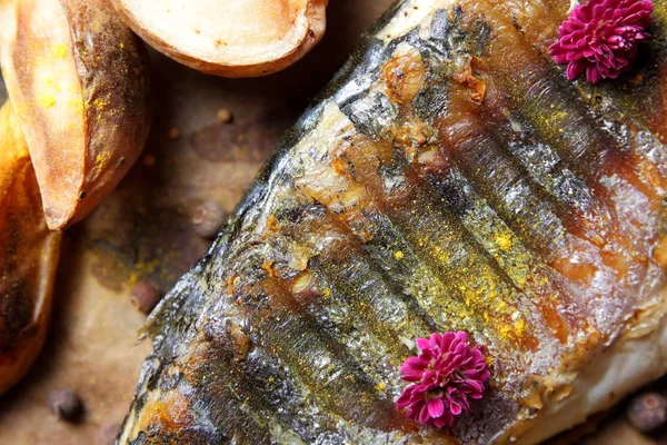 Риба на грилі з сиром, медом, лебединею, калиною, шматочками лимона, запеченою картоплею, рожевими квітами та спеціями на пергаменті — стокове фото