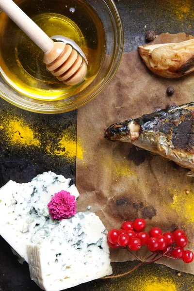 Grillad fisk med ost, honung, rowan, kalina, citronskivor, bakad potatis, rosa blommor och kryddor på bakplåtspapper — Stockfoto