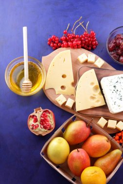 Çeşitli peynirler, limon, nar, mandalina, armut, çilek kartopu ve dağ kül, bal, reçel, pop sanat tarzı ve retro tarzı ahşap tahta rokfor peyniri