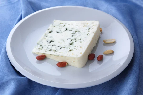 カビや白いプレート上のナッツとチーズ、青の背景、チーズ、青ナプキンにピーナッツの白いプレートに羊のチーズ、チーズとクルミ、ミニマリスト ・ スタイル、レトロなスタイルで — ストック写真