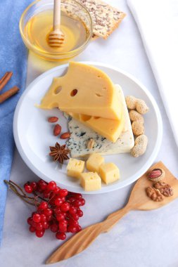 Kalıp peynir ve sert sarı peynir beyaz bir tabak, tatlım, fındık, kırmızı beyaz bir arka planda Noel yemeği, peynir arka plan delikli peynir çilek