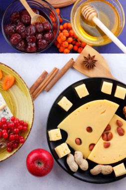 Peynir kalıp, meyve, koyu mavi zemin üzerine delikli sert peynir, siyah saç, meyve, fındık, bal, reçel, Noel yemeği, çok renkli arka plan, retro tarzı üzerinde peynir ile