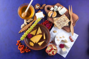 Peynir, yumuşak ve sert peynir, meyve, fındık, bal, Peynir tabağı koyu mavi arka plan, retro tarzı, pop art, vegan Kahvaltı