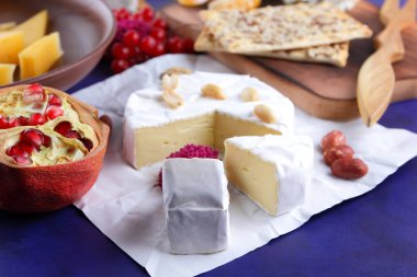 Peynir, camembert peyniri, kırmızı çilek, nar, fıstık tahıl, çiçek, bisküvi, bir mavi arka plan, ahşap masa, pop art, retro tarzı üzerinde beyaz peynir