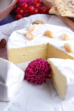 Peynir, camembert peyniri, kırmızı çilek, nar, fıstık tahıl, çiçek, bisküvi, bir mavi arka plan, ahşap masa, pop art, retro tarzı üzerinde beyaz peynir