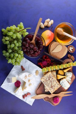 Peyniri, peynir ile kalıp, sert peynir üzerinde ahşap bir masa, armut, bal, Vişne Reçeli, Yeşil üzüm, koyu mavi arka plan, retro tarzı, pop art, Meksika mutfağı