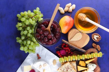 Peyniri, peynir ile kalıp, sert peynir üzerinde ahşap bir masa, armut, bal, Vişne Reçeli, Yeşil üzüm, koyu mavi arka plan, retro tarzı, pop art, Meksika mutfağı