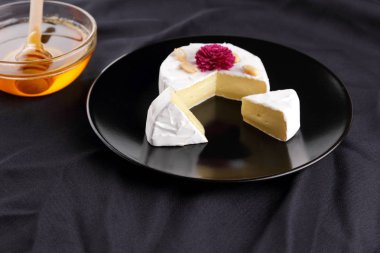 Peynir, camembert bir siyah plaka, tatlım, pembe çiçek, dilimlenmiş peynir küf bir siyah kadife, minimalizm, siyah bir zemin üzerine peynir ile