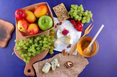 Camembert, kalıp, elma, Yeşil üzüm, bal, kırmızı meyveler kartopu, fıstık, koyu mavi arka plan, pop art, retro tarzı, armut, sağlıklı gıda, parşömen kağıt, ahşap masa, sanat üzerine kaşar peynir