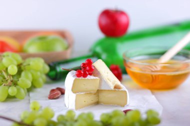 Brie peyniri ile Fransız Camembert Yeşil üzüm, bal brie peyniri ile arka plan, kırmızı meyveler ve pembe çiçek, fıstık, sağlıklı gıda yeşil şişe ile Kahvaltı