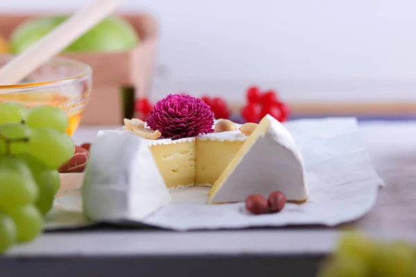Camembert with honey, red berries and apples, cheese with green grapes, peanuts and pink flower, healthy food, French breakfast with brie in retro style
