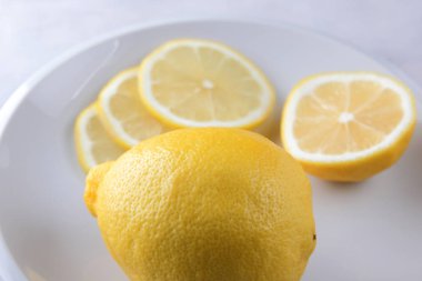 Limon mermer bir zemin üzerine minimalist tarzda, beyaz bir tabak, sağlıklı gıda, vegan, pop art, beyaz zemin üzerine sarı limon limon dilimleri