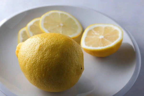 在一个极简风格的大理石背景下的柠檬片 白色盘子上的柠檬 健康食品 纯素食 流行艺术 白色背景下的黄色柠檬 — 图库照片