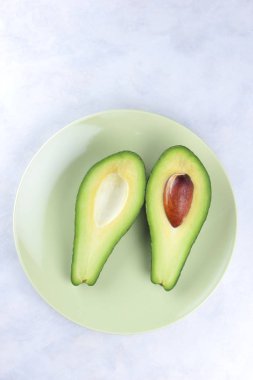 Beyaz bir arka planda, yeşil meyve, tropikal meyve, yeşil bir tabak içinde avokado avokado bir mermer arka plan, sağlıklı gıda, vegan, minimalizm kesmek