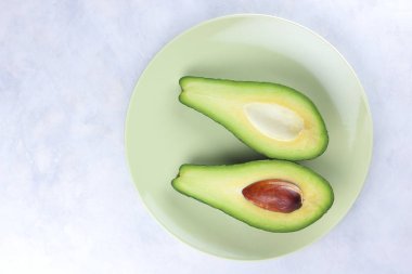 Beyaz bir arka planda, yeşil meyve, tropikal meyve, yeşil bir tabak içinde avokado avokado bir mermer arka plan, sağlıklı gıda, vegan, minimalizm kesmek