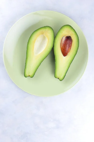 鳄梨在白色背景的绿色盘子里 绿色水果 热带水果 在大理石背景下切鳄梨 健康食品 极简主义 — 图库照片