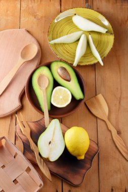 Avokado, limon ve armut ahşap zemin, sarı plaka ile armut dilimleri, ahşap tahta ve kutusu, avokado retro tarzı, ahşap arka plan ile meyve dilimlenmiş