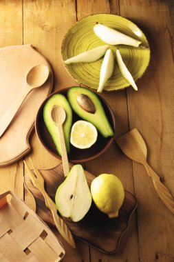 Avokado, limon ve armut ahşap zemin, sarı plaka ile armut dilimleri, ahşap tahta ve kutusu, avokado retro tarzı, ahşap arka plan ile meyve dilimlenmiş