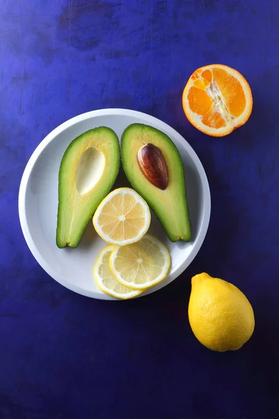 Αβοκάντο Λεμόνι Και Μισό Πορτοκάλι Ένα Άσπρο Πιάτο Τροπικά Φρούτα — Φωτογραφία Αρχείου