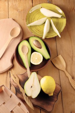 Avokado, limon ve bir ahşap arka plan, sarı plaka armut dilimleri, ahşap tahta ve kutusu, retro tarzı, ahşap arka plan ile meyve, dilimlenmiş avokado ile armut sanat