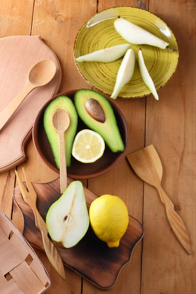 Avokado, limon ve bir ahşap arka plan, sarı plaka armut dilimleri, ahşap tahta ve kutusu, retro tarzı, ahşap arka plan ile meyve, dilimlenmiş avokado ile armut sanat