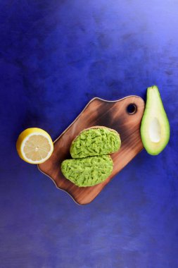 Avokado ve limon ekmek üzerinde bir tahta masa, avokado yapıştırırken, ahşap tahta sandviç yayılan ultraviyole arka planda, yeşil ile yapılan avokado, yarım limon, vejetaryen yemek, Latin Amerika mutfağı ile