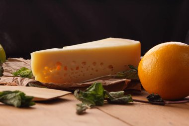 Sert peynir, limon, limon ve nane bir ahşap arka plan, tahta spatula, nane yaprakları ile peynir ve delik, rustik tarzı, parşömen peynir, sağlıklı gıda, vegan