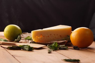 Sert peynir, limon, limon ve nane bir ahşap arka plan, tahta spatula, nane yaprakları peynir ve delik, rustik tarzı, parşömen peynir, sağlıklı gıda, sanat ile