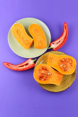 Mor bir arka planda bir kabak ve kırmızı biber yeşil bir tabak, sebze pop art, minimalizm, turuncu ve kırmızı sebze mor arka plan, Bulgar biber, vegan, sanat yarısı kabak