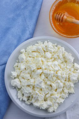 Beyaz arka plan, yumuşak peynir bir mavi peçete, tatlım, sağlıklı gıda, Fransız Kahvaltı, Amerikan mutfağı, minimalizm, süt ürünleri ile bal ile taze peynir lor keçi sütü ile