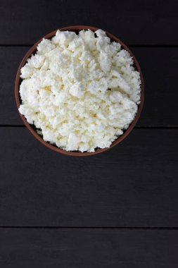 Taze peynir bir koyu ahşap arka plan, yumuşak peynir bir çanak çömlek, rustik tarzı, sağlıklı gıda, Fransız Kahvaltı, Amerikan mutfağı, minimalizm, kopya alanı süzme peynir süt ürünleri