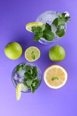 Mojito ultraviyole bir arka plan, nane, limon ve kireç, yaz dinlenmek için bir meşrubat, mor bir arka plan, bir pop sanat içki, yarım limon ve kireç, minimalizm kokteylde bir kokteyl