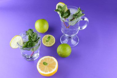 Mojito ultraviyole bir arka plan, nane, limon ve kireç, yaz dinlenmek için bir meşrubat, mor bir arka plan, bir pop sanat içki, yarım limon ve kireç, minimalizm kokteylde bir kokteyl