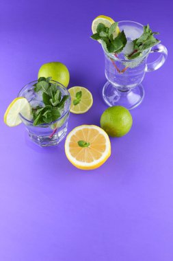 Mojito ultraviyole bir arka plan, nane, limon ve kireç, yaz dinlenmek için bir meşrubat, mor bir arka plan, bir pop sanat içki, yarım limon ve kireç, minimalizm kokteylde bir kokteyl