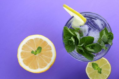 Mojito ultraviyole bir arka plan, nane, limon ve kireç, yaz dinlenmek için bir meşrubat, mor bir arka plan, bir pop sanat içki, yarım limon ve kireç, minimalizm kokteylde bir kokteyl