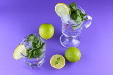 Mojito ultraviyole bir arka plan, nane, limon ve kireç, yaz dinlenmek için bir meşrubat, mor bir arka plan, bir pop sanat içki, yarım limon ve kireç, minimalizm kokteylde bir kokteyl