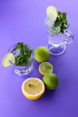 Mojito ultraviyole bir arka plan, nane, limon ve kireç, yaz dinlenmek için bir meşrubat, mor bir arka plan, bir pop sanat içki, yarım limon ve kireç, minimalizm kokteylde bir kokteyl