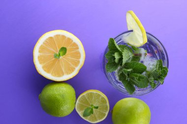 Mojito ultraviyole bir arka plan, nane, limon ve kireç, yaz dinlenmek için bir meşrubat, mor bir arka plan, bir pop sanat içki, yarım limon ve kireç, minimalizm kokteylde bir kokteyl