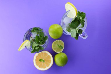 Mojito ultraviyole bir arka plan, nane, limon ve kireç, yaz dinlenmek için bir meşrubat, mor bir arka plan, bir pop sanat içki, yarım limon ve kireç, minimalizm kokteylde bir kokteyl